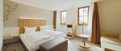 Una habitación de hotel con una cama grande, un escritorio, una silla y una mesita.