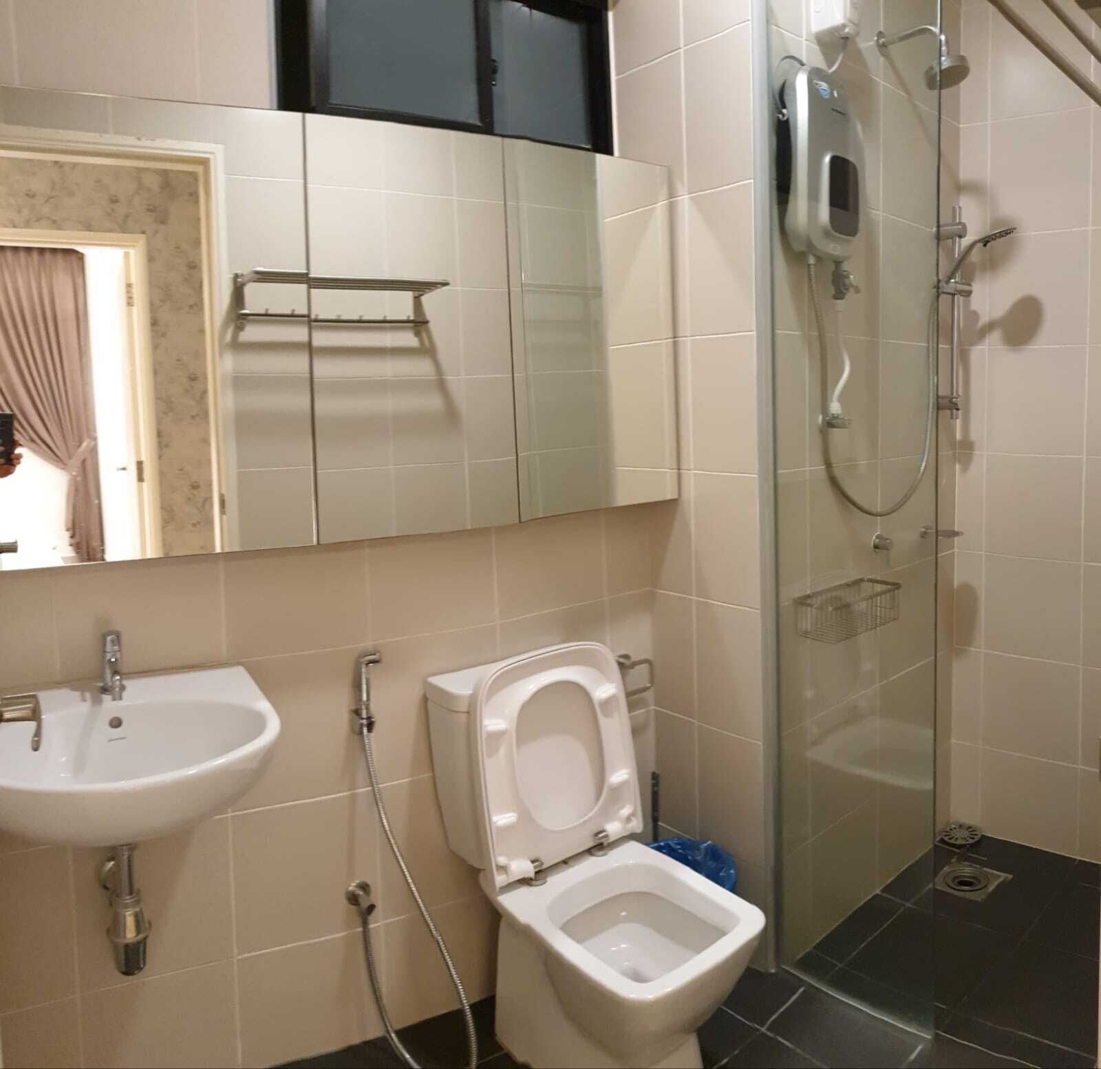 Un baño con lavamanos, inodoro y ducha con paredes de vidrio.