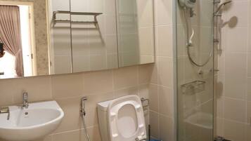 Un baño con lavamanos, inodoro y ducha con paredes de vidrio.