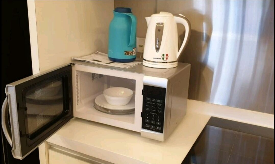 A compact microwave with a built-in oven, a small bowl, and a kettle on top.