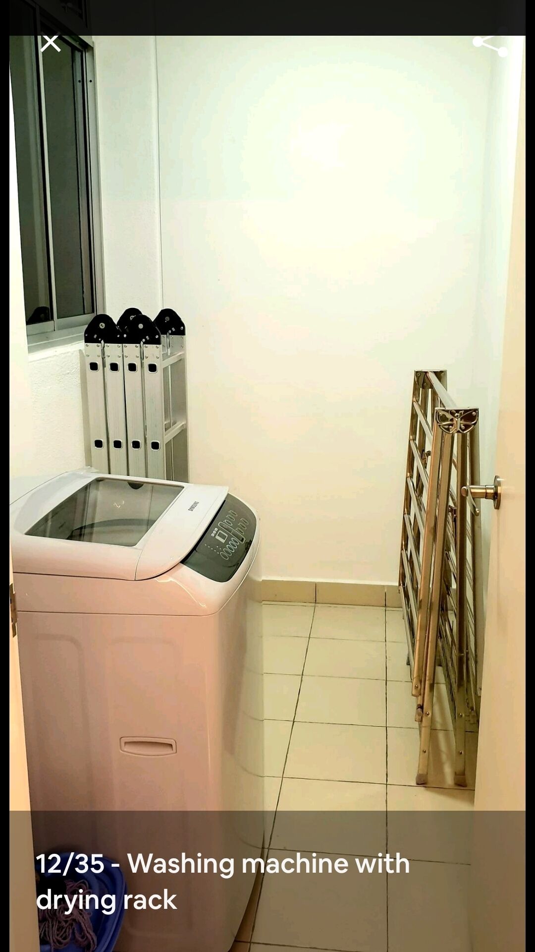 A laundry area with a washing machine and a drying rack.