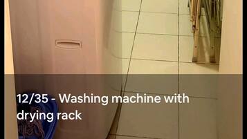 A laundry area with a washing machine and a drying rack.