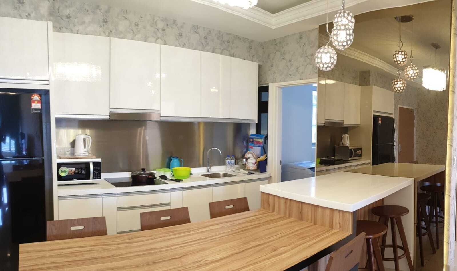 A modern kitchen with white cabinets, a wooden countertop, and a bar area with stools.