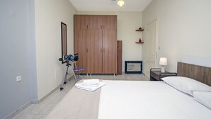 A bedroom with a large bed, a wooden wardrobe, a desk with a lamp, and a telescope on a tripod.
