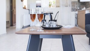 A dining table with two glasses of amber liquid, a black tray with small items, and a modern kitchen in the background.