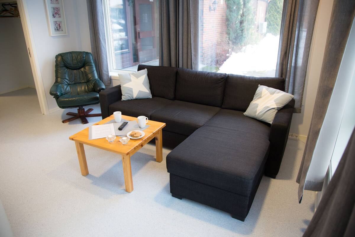 Uma sala de estar moderna com um sofá seccional, uma mesa de centro de madeira e uma poltrona de couro.