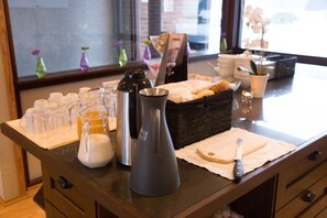 A breakfast buffet setup with various food items, a coffee maker, and decorative elements. - Lunde Vandrerhjem (Nome)