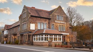 A historic building with a stone facade, multiple windows, and a sign indicating it is the Strutt Arms Hotel. - The Strutt Arms (Belper)