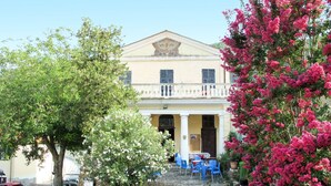 A building with a balcony, a stone wall, and a tree with pink flowers. - Nice apartment for 6 people with WIFI, pool, TV, patio, pets allowed and panoramic view (Prelà Castello)