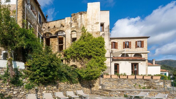 A pool area with stone walls and a pool, surrounded by lounge chairs and a building with stone architecture. - Nice apartment for 6 people with WIFI, pool, TV, patio, pets allowed and panoramic view (Prelà Castello)