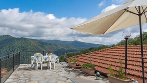 A terrace with stone flooring, a table with chairs, potted plants, and a large umbrella. - Nice apartment for 8 people with pool, WIFI, TV, patio, pets allowed and panoramic view (Prelà Castello)
