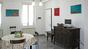 Un comedor con una mesa lista para dos personas, un mueble con un televisor y obras de arte en las paredes.