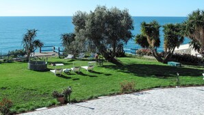 Un espacio al aire libre con césped, un conjunto de asientos y vistas al mar.