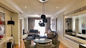 A modern living room with a round glass table, two sofas, and a large mirror.