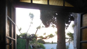 An open doorway leading to a stone-paved area with a lawn and a tree.