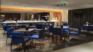 A modern dining area with blue chairs and tables, a long counter with a bar, and a polished floor. - Jinjiang Inn (Beijing)