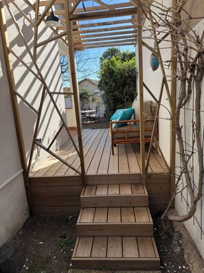 A wooden deck with a pergola, a bench, and a small table.