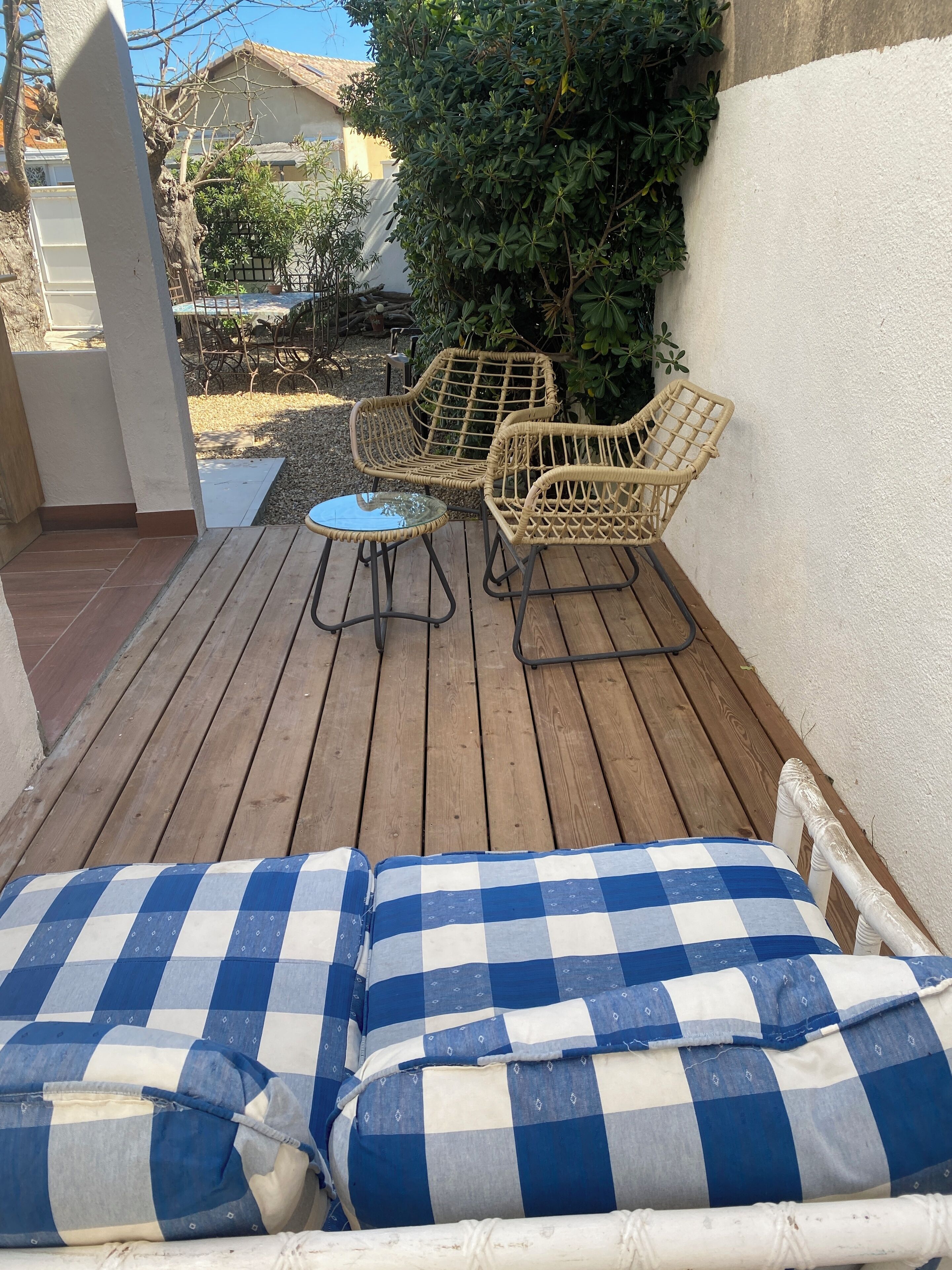 A wooden deck with wicker furniture and checkered cushions.