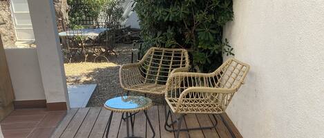 A wooden deck with wicker furniture and checkered cushions.