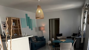 A modern living room with a dining area, featuring a sofa, chairs, a table, and a hanging light fixture. - Air-conditioned villa with garden in the center of Marseillan (Marseillan)