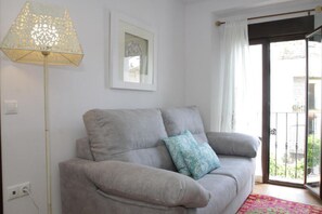 Un canapé gris avec un coussin à motifs, un lampadaire et un tableau encadré accroché au mur.