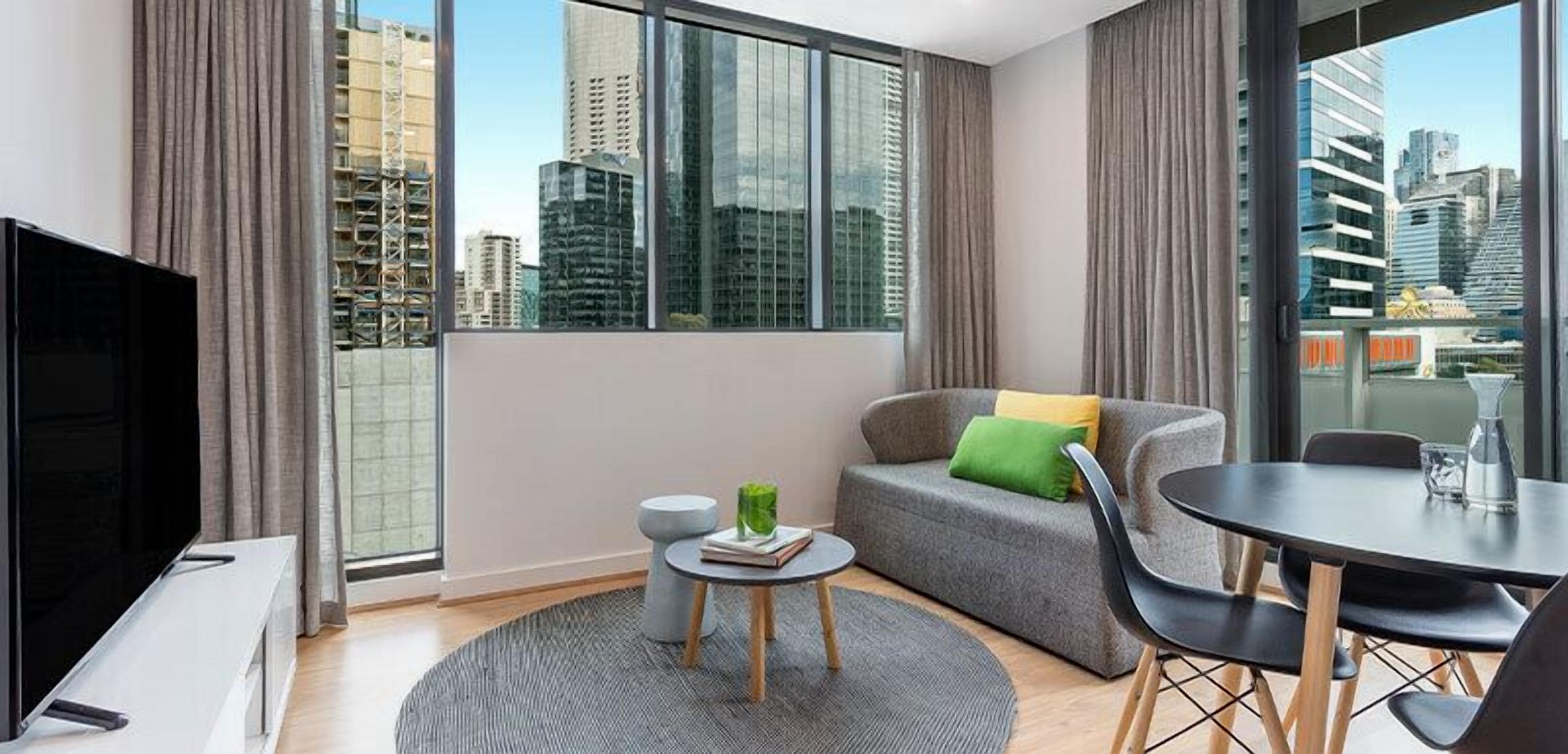 A modern living room with a sofa, a small round table, and a TV.
