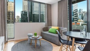 A modern living room with a sofa, a small round table, and a TV. - Opus tower (Southbank)
