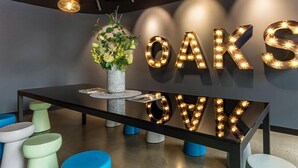 A modern interior with a table, chairs, and illuminated letters spelling "OAKS" on the wall. - Opus tower (Southbank)