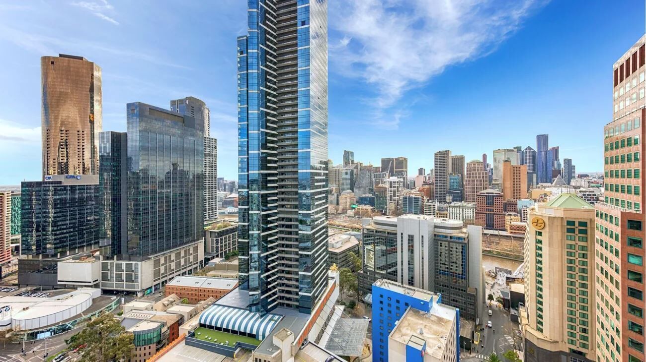 A cityscape with modern high-rise buildings, including a prominent skyscraper with a reflective glass facade.