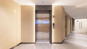 Elevador moderno em corredor de hotel, com design elegante e painel de controle na parede.