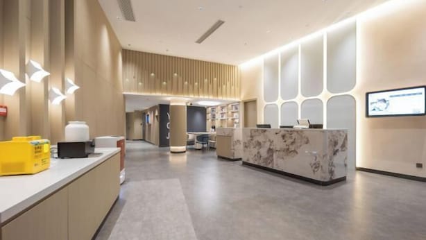 Uma área de recepção moderna com balcão de mármore, espaço de estar e televisão na parede.