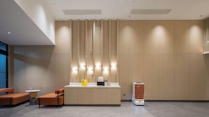 Uma área de recepção moderna com balcão, assentos e um painel fixado na parede.