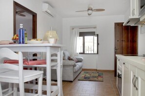 A compact living space with a dining area, a sofa, a kitchen, and a window.