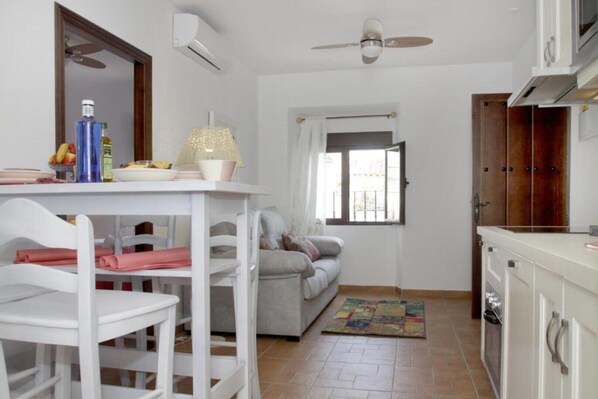 A compact living space with a dining area, a sofa, a kitchen, and a window.