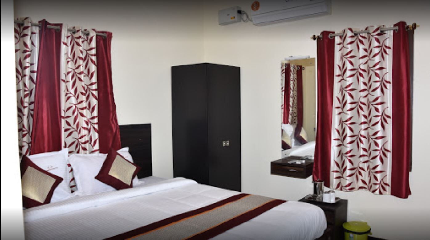 Una habitación de hotel con cama, armario, espejo y cortinas.