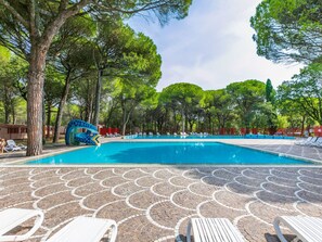 Une piscine dotée de chaises longues et d’une terrasse ornée de motifs en mosaïque.