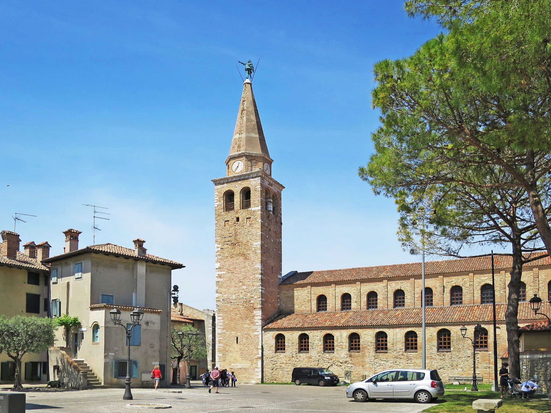 A historic square with a prominent tower, traditional buildings, and a clear blue sky.