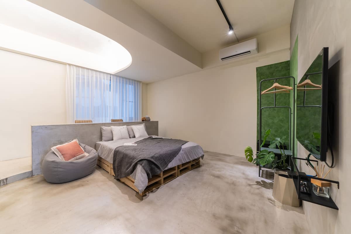 Ein modernes Schlafzimmer mit Bett, Sitzsack und Wand-Fernseher.
