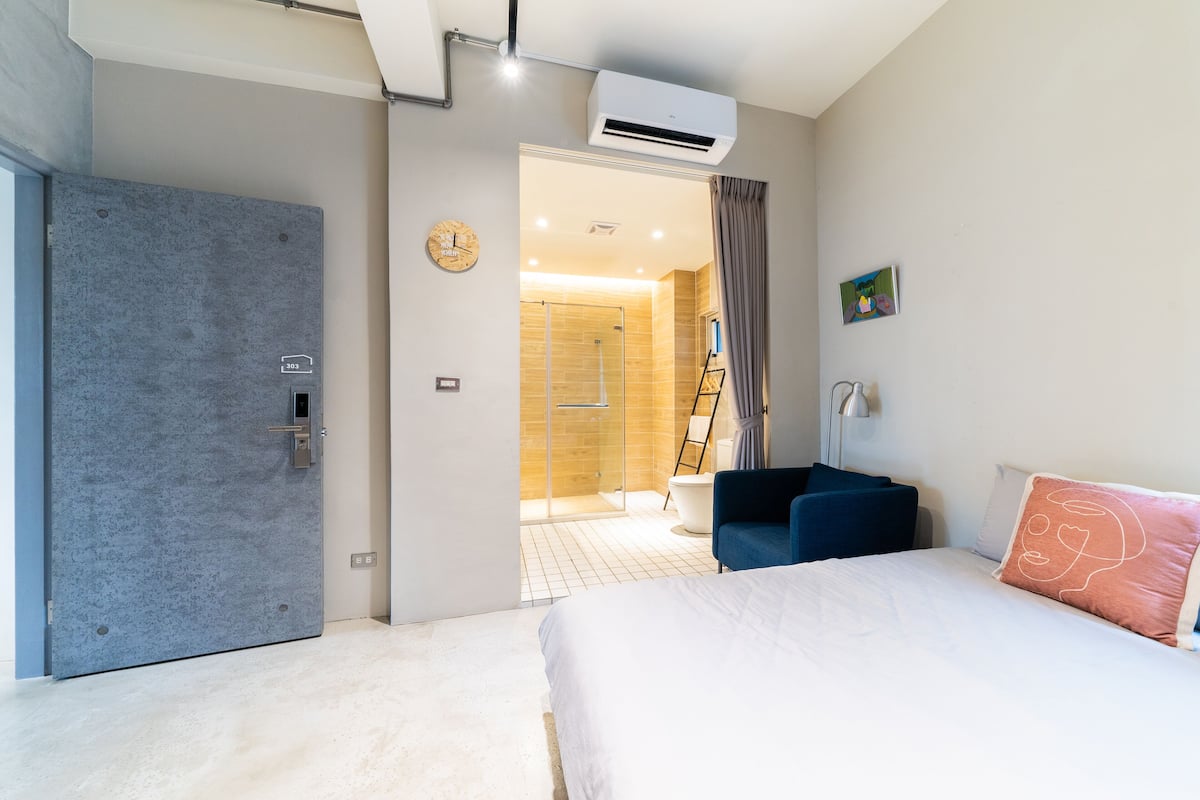 Ein modernes Hotelzimmer mit einem großen Bett, einem Schreibtisch und einer Duschkabine.