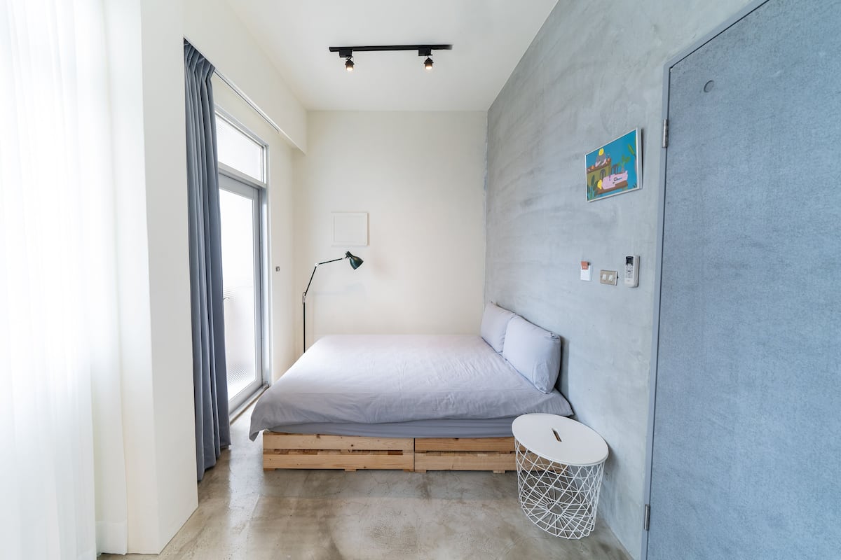 Ein Schlafzimmer mit Bett, Nachttisch, Lampe, einem kleinen runden Tisch und einem Wandbild.