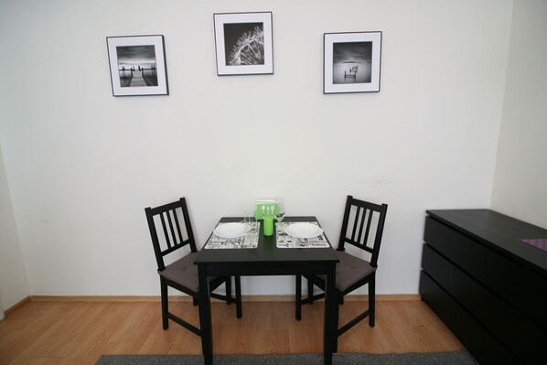 Un comedor con una mesa preparada para dos, dos sillas y tres cuadros en la pared.