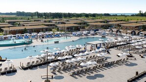 A resort with multiple swimming pools, sun loungers, and umbrellas. - Cosy apartment for 5 people with pool, A/C, WIFI, TV, terrace and pets allowed (San Michele Al Tagliamento)