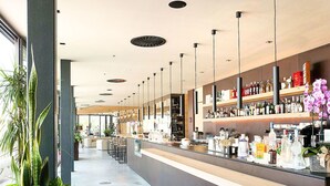 A modern bar area with a long counter, multiple hanging lights, and shelves stocked with bottles. - Cosy apartment for 5 people with pool, A/C, WIFI, TV, terrace and pets allowed (San Michele Al Tagliamento)