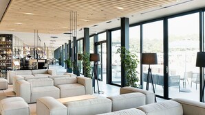 A modern hotel lobby with a long reception desk, large windows, and a seating area with sofas and tables. - Cosy apartment for 5 people with pool, A/C, WIFI, TV, terrace and pets allowed (San Michele Al Tagliamento)