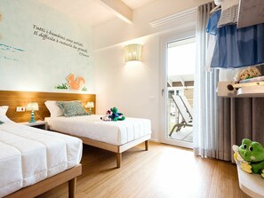 Quarto de hotel com duas camas, um mural com uma citação, uma luminária e vista para o exterior.