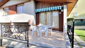 Une maison à deux étages dotée d’un patio comprenant une table et des chaises, un espace salon couvert et un portail en métal.