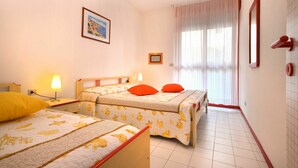 Habitación de hotel con dos camas, un ventanal con cortinas, un cuadro enmarcado en la pared y suelo de baldosas.