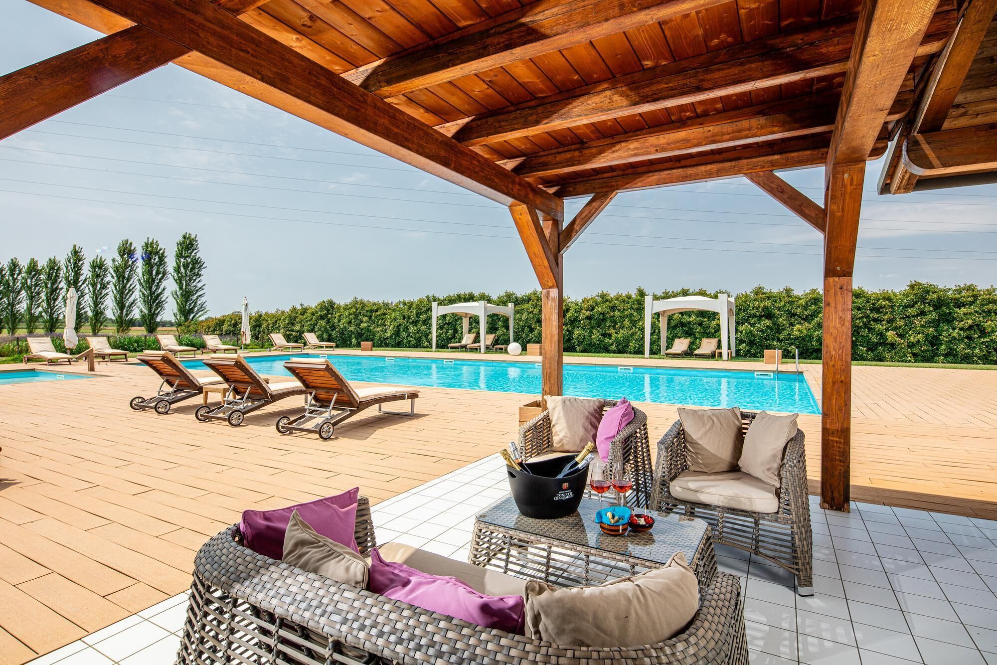 A covered outdoor area with a pool, lounge chairs, and a wicker sofa.
