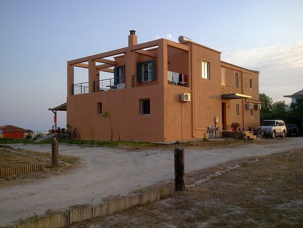 A modern two-story building with a flat roof, large windows, and a balcony.