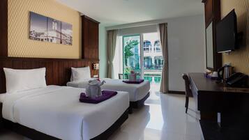 Habitación de hotel con dos camas, un escritorio, un televisor y un balcón con vistas a edificios.